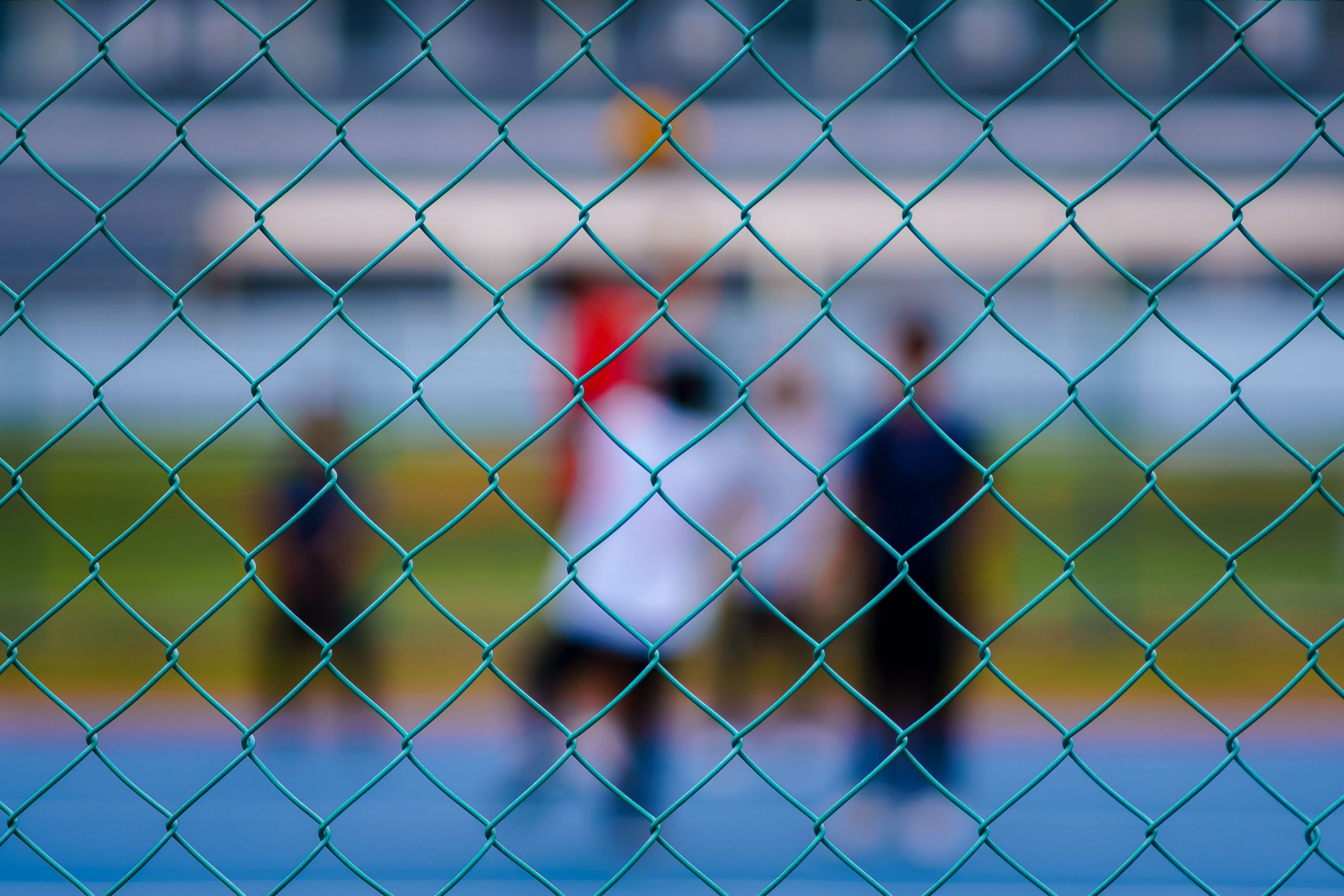 Joueurs de sport derrière clôture bleue extérieure