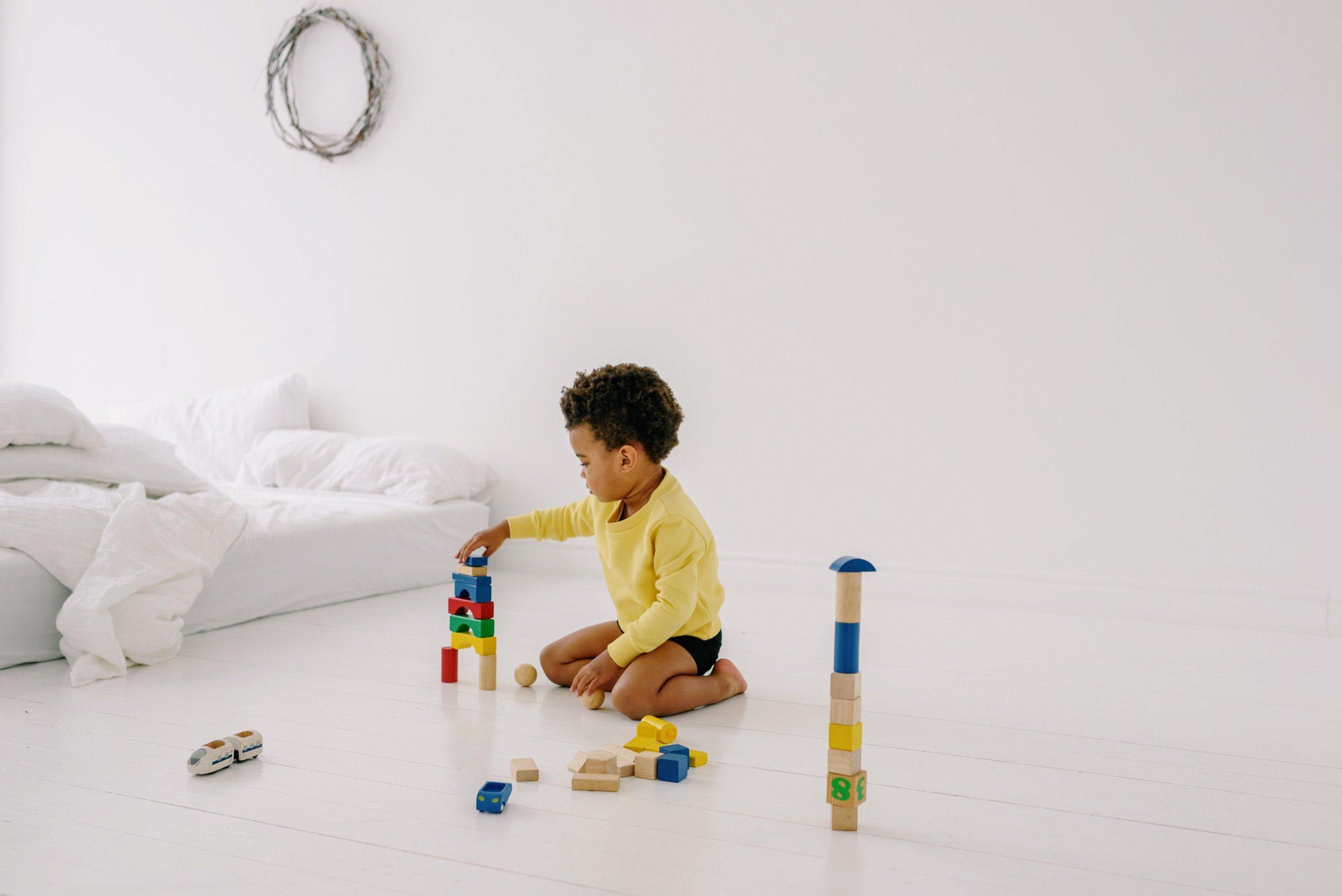 Jeune enfant jouant cubes bois sur sol blanc