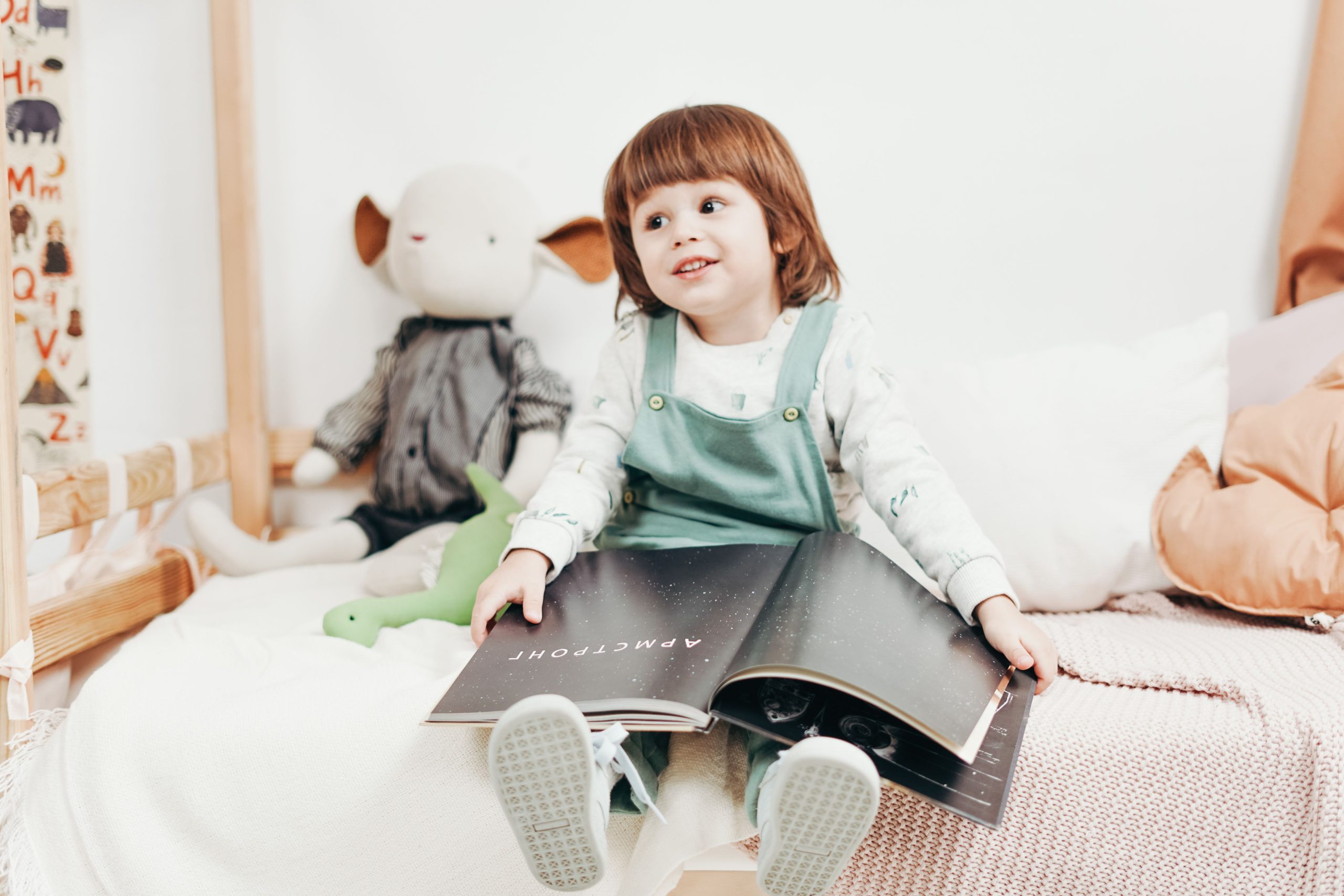 Enfant lisant un livre assis sur lit chambre lumineuse
