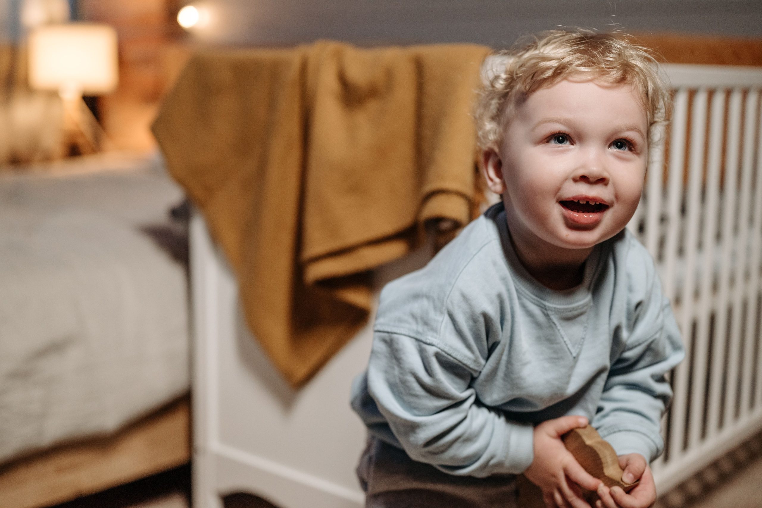 Petit enfant blond jouant jouet bois chambre cosy