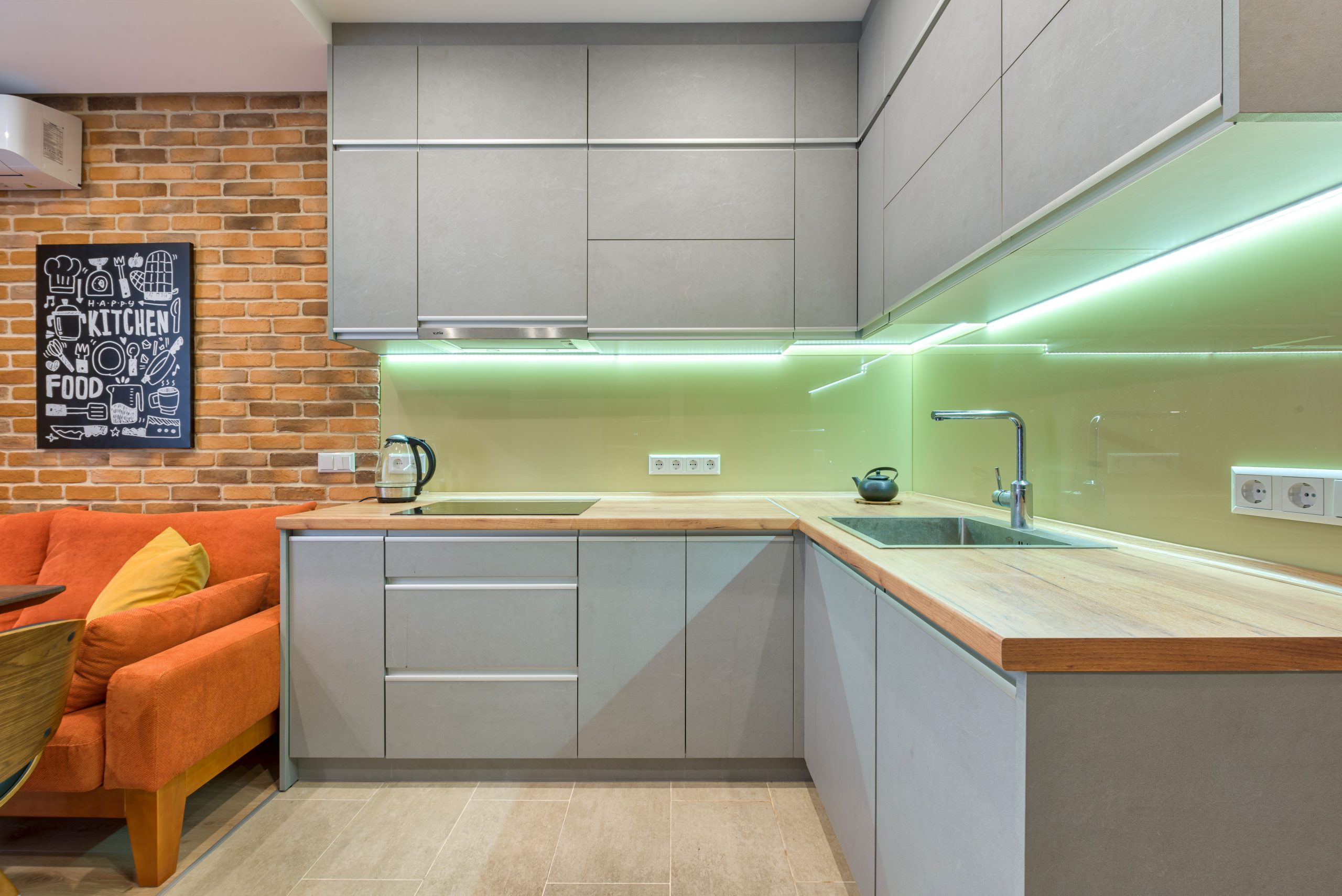 Cuisine aux meubles gris avec mur en briques