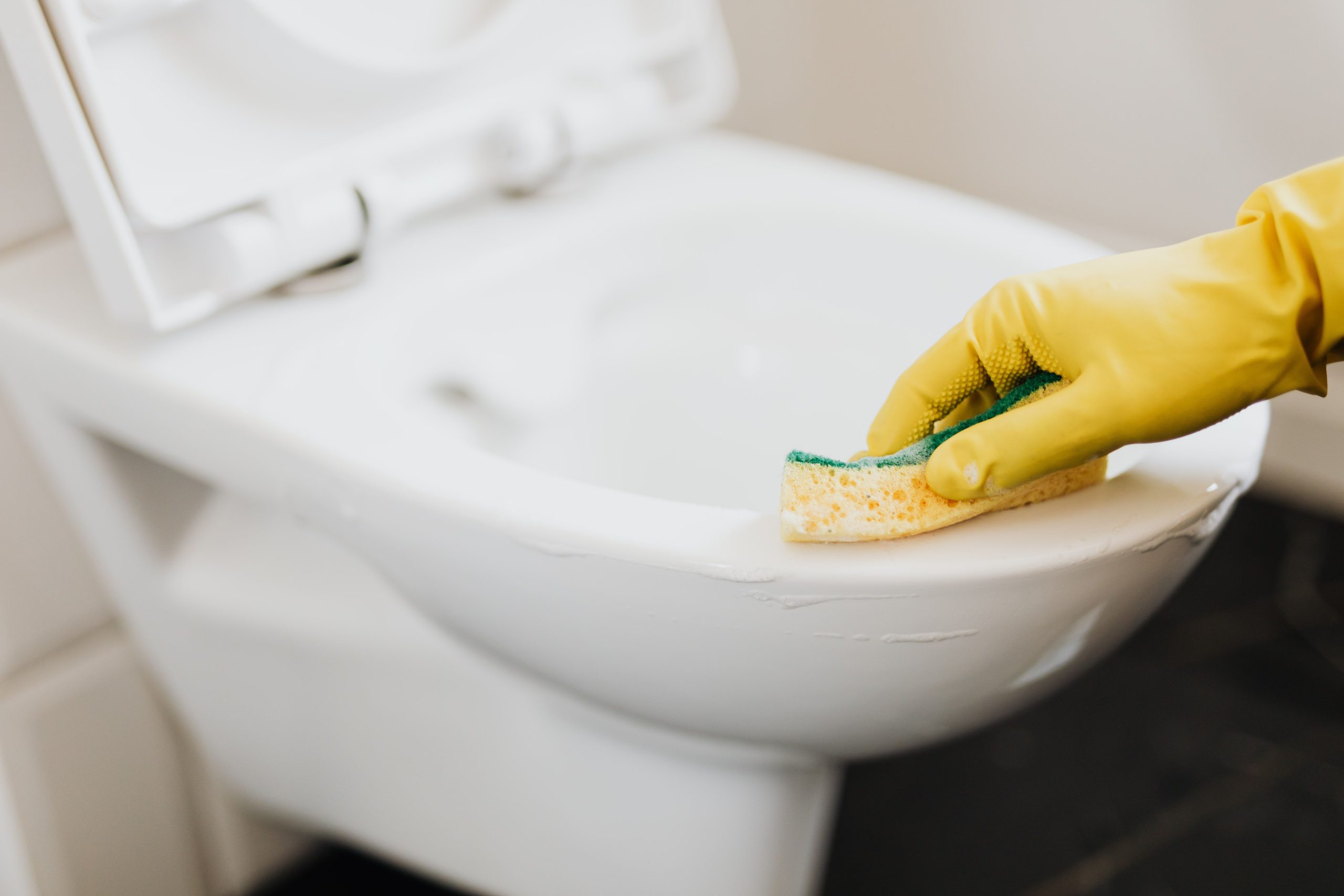 Femme en gants jaunes récurant la cuvette avec un detergent